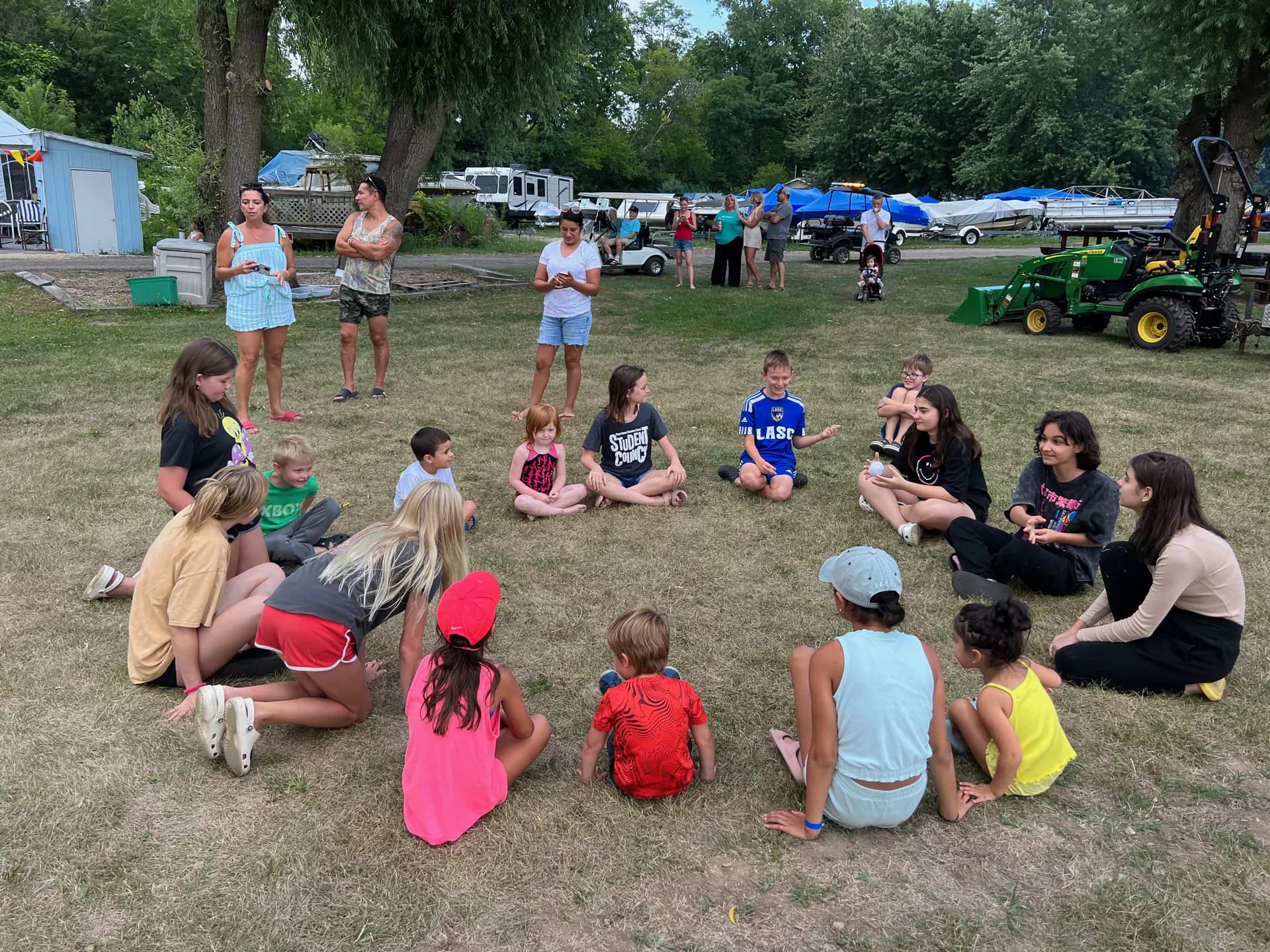 Kids sitting in a circle for a group game on the grass