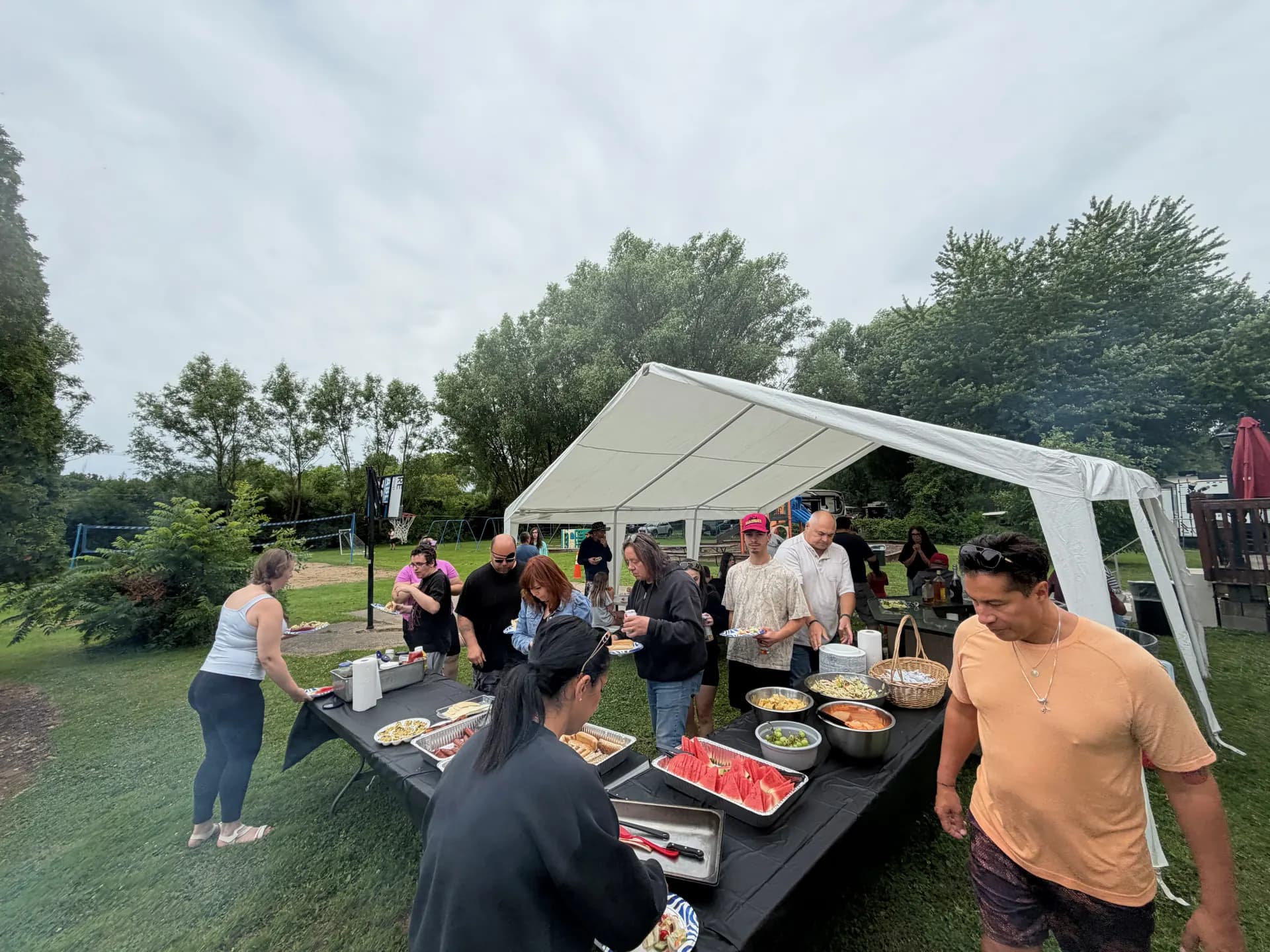 A potluck cookout under a white party tent